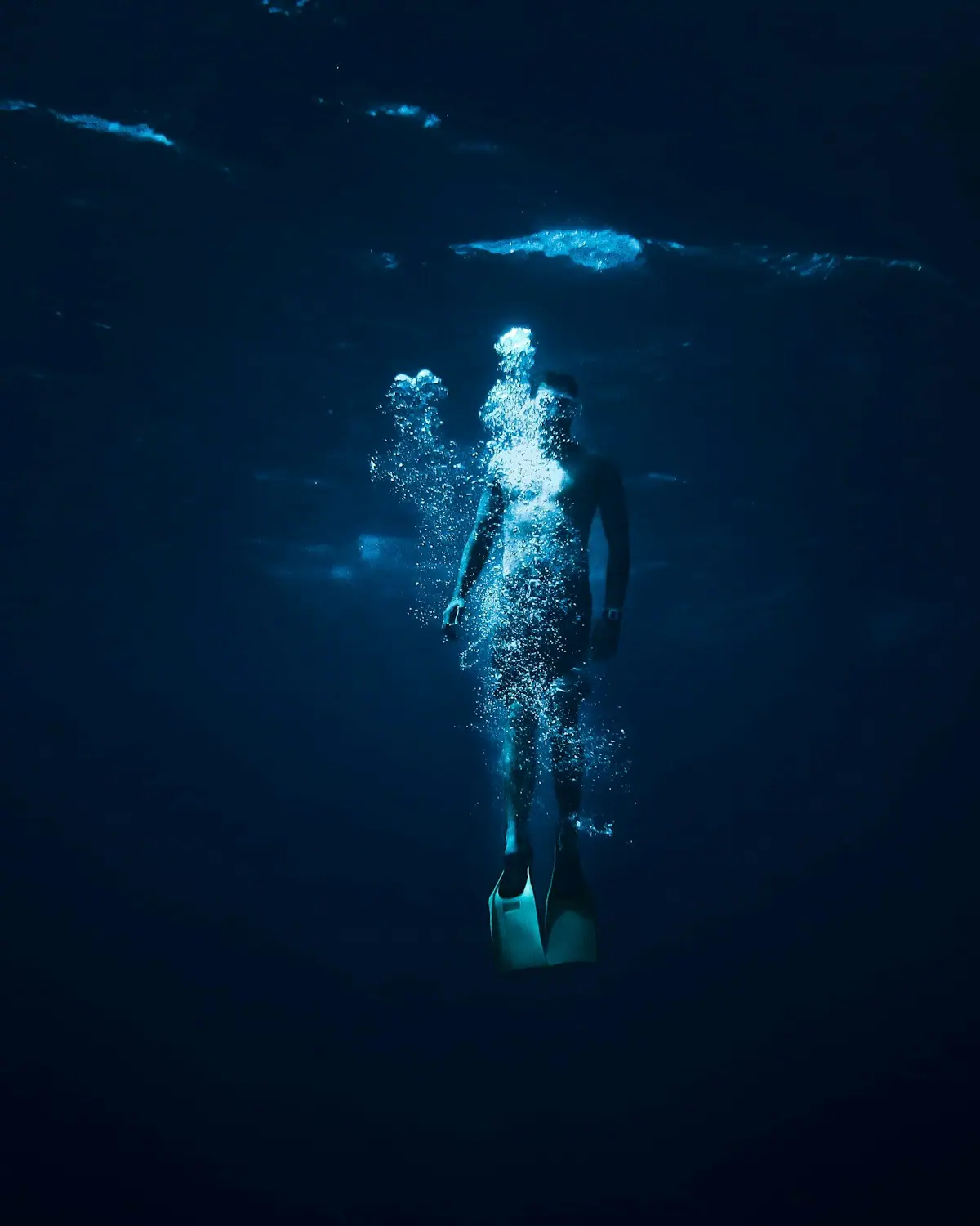 A freediver descending through deep blue water