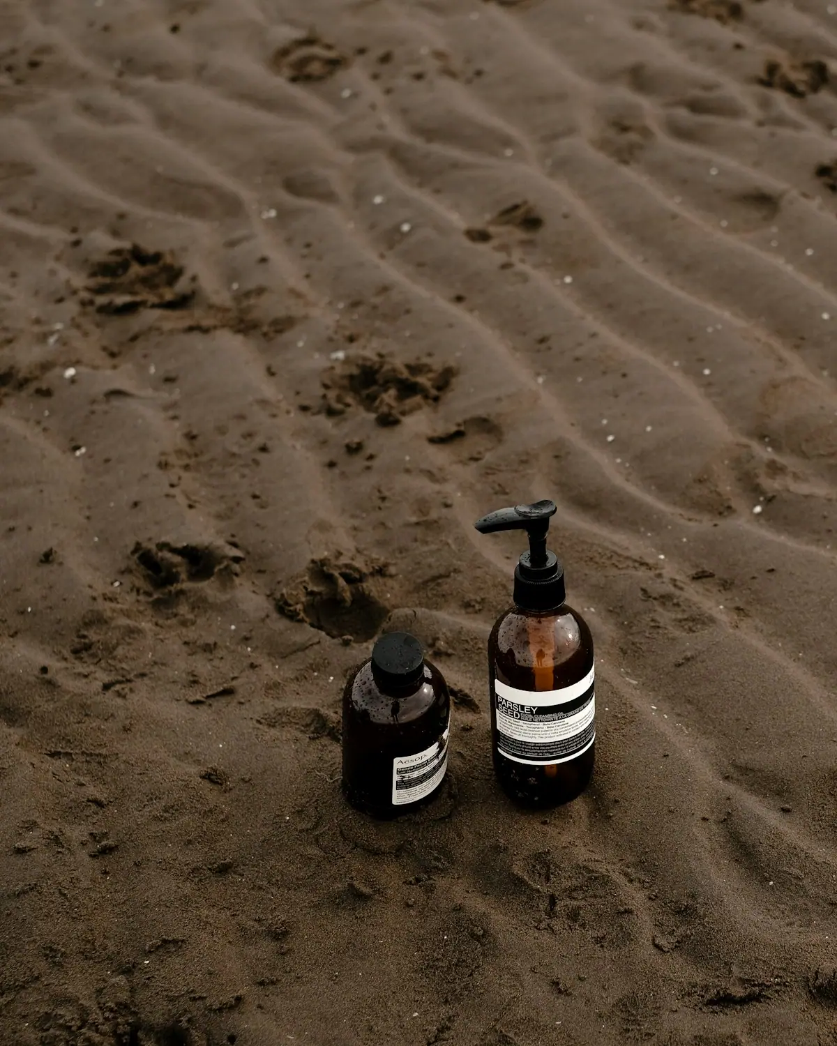 Botanical skincare bottles resting on warm sand